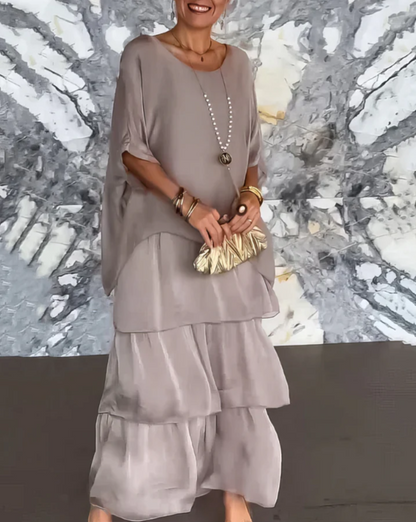 Robe longue fluide gris clair, manches chauve-souris, encolure ronde, volants superposés