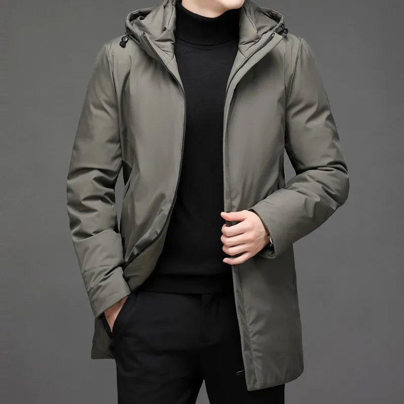 Veste longue d’hiver à capuche vert olive, fermeture zippée, poches latérales visibles.