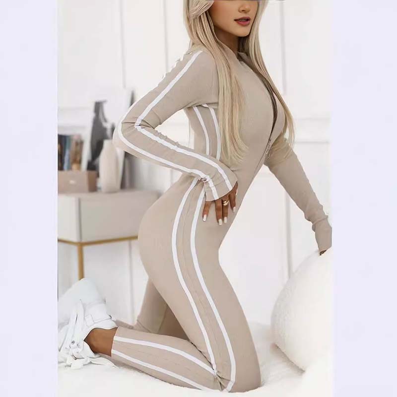 Combinaison sportive ajustée beige à bandes blanches, zip et manches longues.