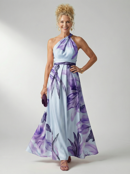 Robe longue fleurie à col halter, ceinture nouée, motifs violets sur fond clair.