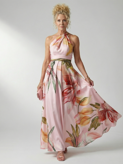 Robe longue fleurie à col halter, ceinture nouée, motifs roses et verts sur fond clair.