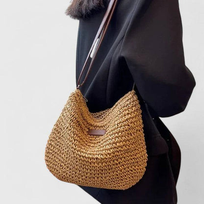 Sac en paille dorée avec bandoulière marron, porté sur l’épaule, motif rectangulaire.