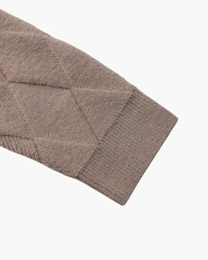 Manche du gilet en tricot mocha, bas côtelé et motif losanges.