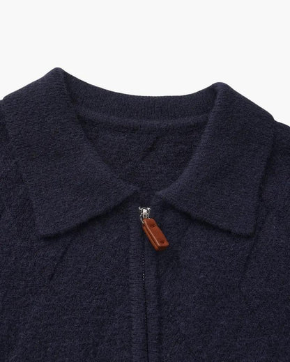 Capuche et fermeture éclair du gilet marine, tirette en cuir brun.