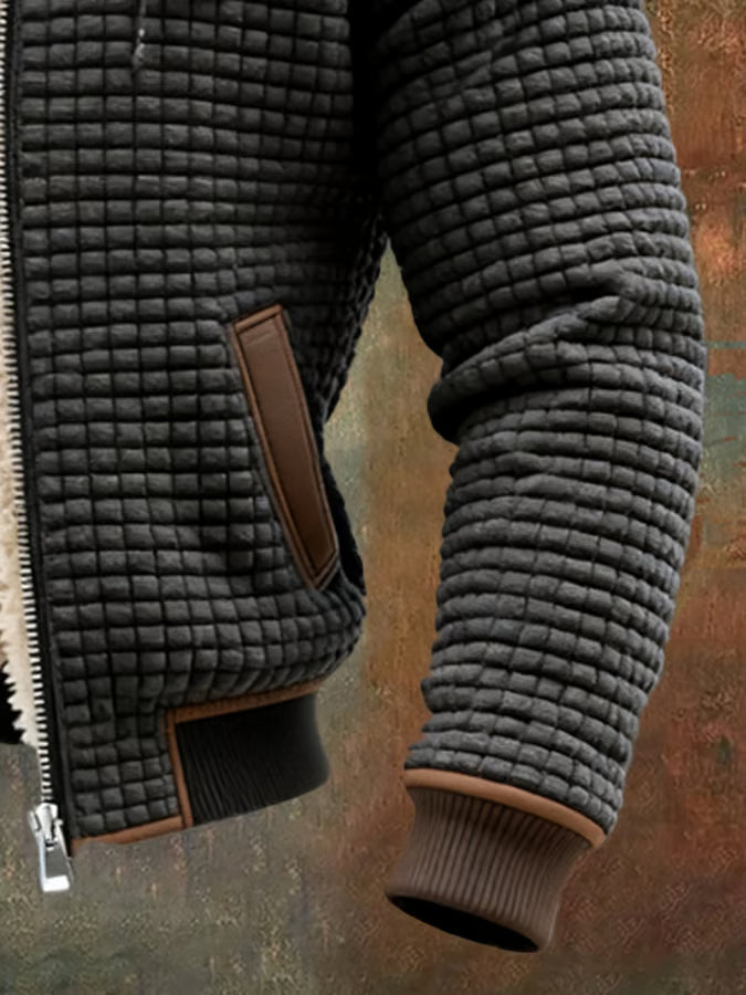 Veste bomber noire: poche zippée en cuir brun et texture gaufrée visible, bord sherpa.